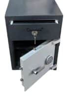 Image of TEMPO CAISSE CF-60 a two-tone (dark gray and light gray) safe. The safe door is ajar, showing a round, silver keypad with push buttons and a small key hanging inside. A narrow drawer below the main compartment is also slightly open. The background is plain and light. This safe appears to offer both electronic and key lock options.